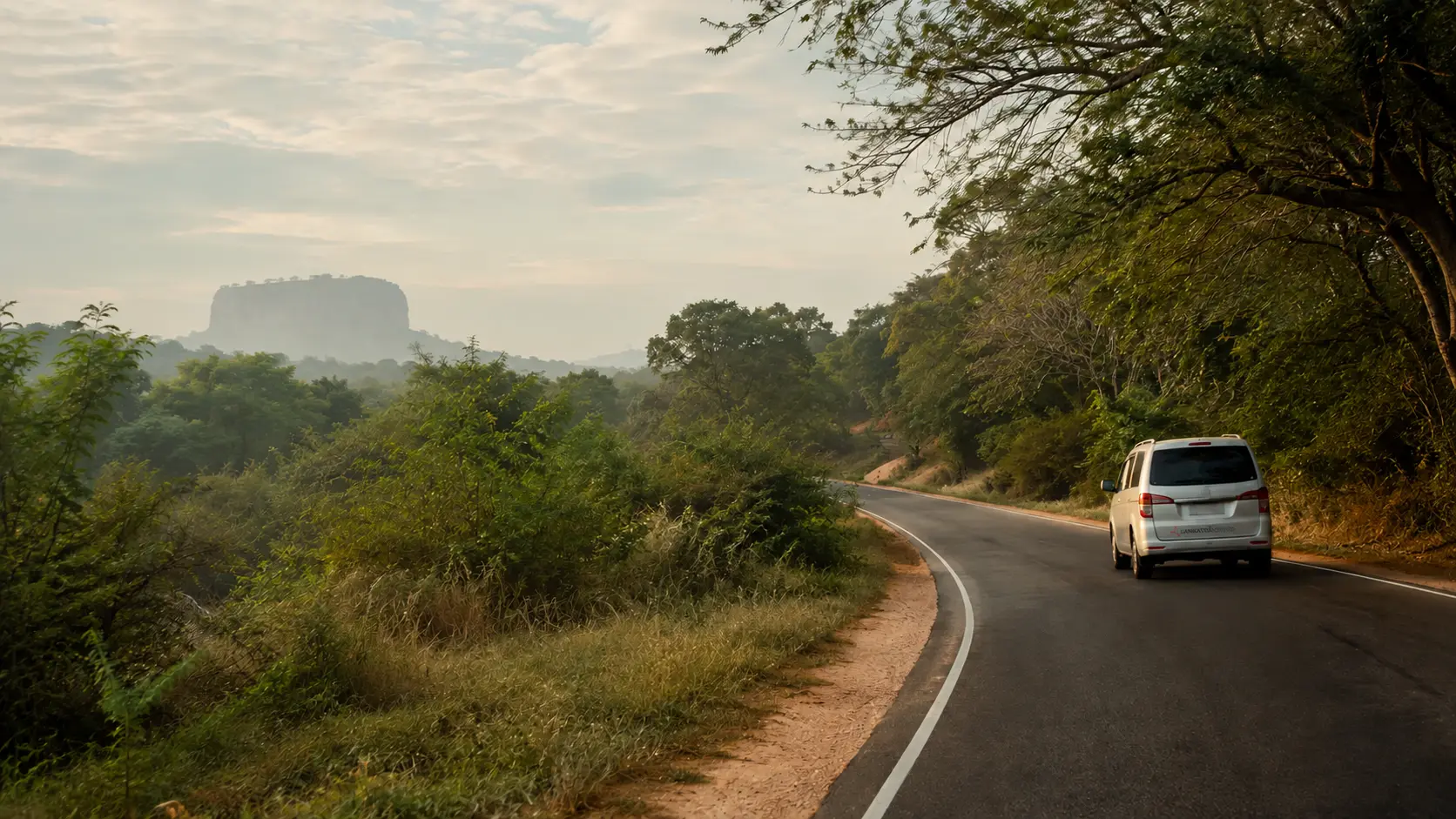 A private vehicle travelling a quiet dry-zone road toward Sigiriya